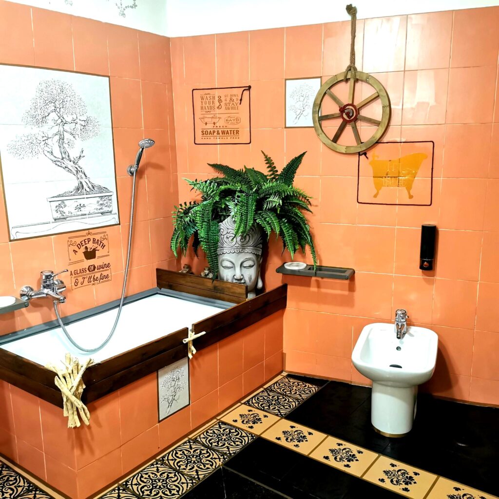 Bagno con vasca vintage, pareti arancio e dettagli orientali in stile artistico
