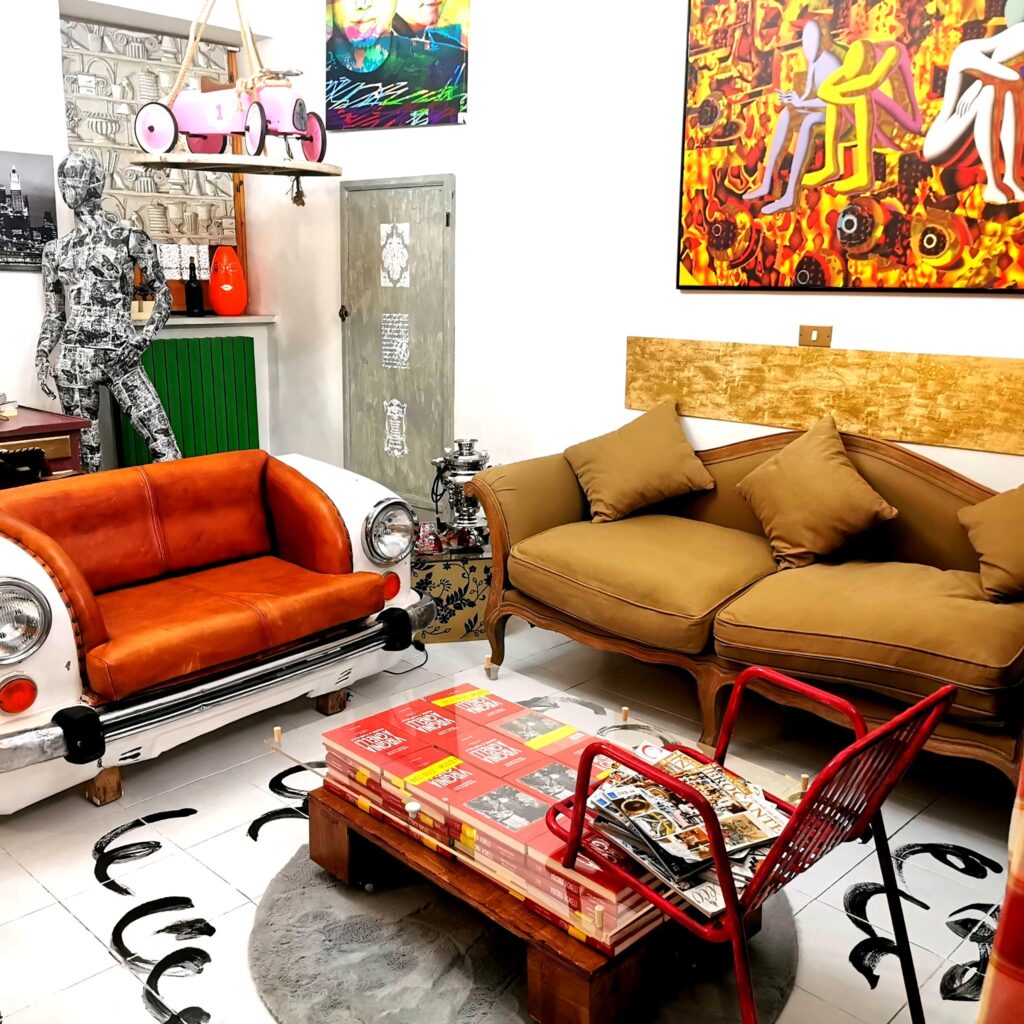 Salone d'arte con divano-auto vintage e installazioni contemporanee